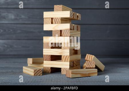 Jenga tower and wooden blocks on grey table. Board game Stock Photo