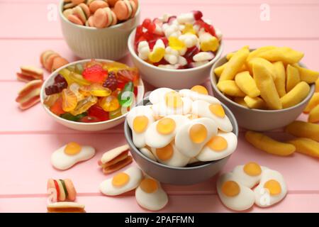 Many different delicious gummy candies on pink wooden table Stock Photo
