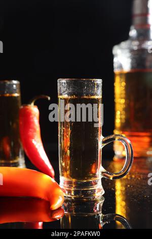 Red hot chili peppers and vodka on black table Stock Photo