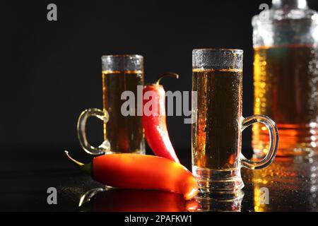 Red hot chili peppers and vodka on black table Stock Photo