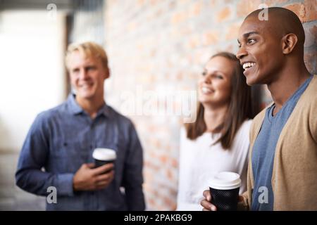 Having a good laugh with colleagues. a diverse group of friends hanging out in a corridor. Stock Photo