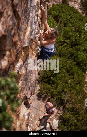 Using every ounce of her strength to reach the top. a young woman scaling a mountain rockface. Stock Photo