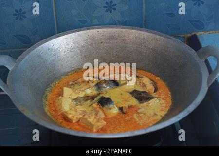 photo of tuna fish and white tofu in yellow spice sauce on a frying pan. Indonesian traditional food photo concept. Stock Photo