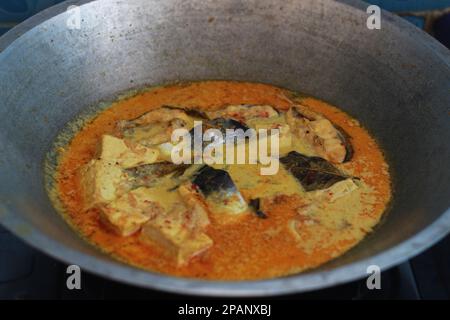 photo of tuna fish and white tofu in yellow spice sauce on a frying pan. Indonesian traditional food photo concept. Stock Photo