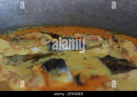 photo of tuna fish and white tofu in yellow spice sauce on a frying pan. Indonesian traditional food photo concept. Stock Photo