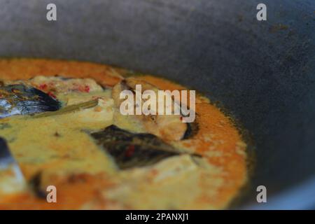 photo of tuna fish and white tofu in yellow spice sauce on a frying pan. Indonesian traditional food photo concept. Stock Photo