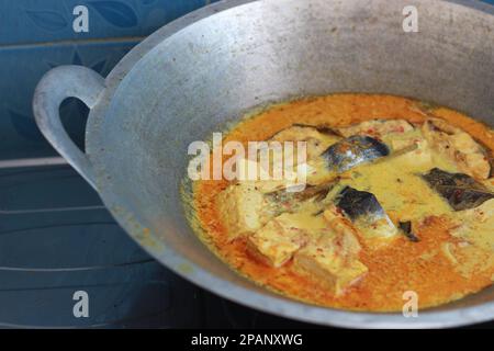 photo of tuna fish and white tofu in yellow spice sauce on a frying pan. Indonesian traditional food photo concept. Stock Photo