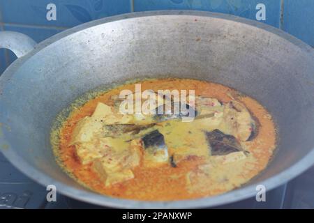 photo of tuna fish and white tofu in yellow spice sauce on a frying pan. Indonesian traditional food photo concept. Stock Photo