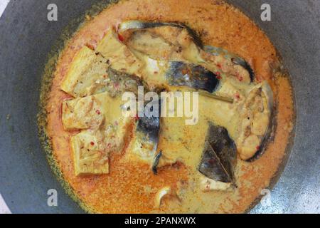 photo of tuna fish and white tofu in yellow spice sauce on a frying pan. Indonesian traditional food photo concept. Stock Photo