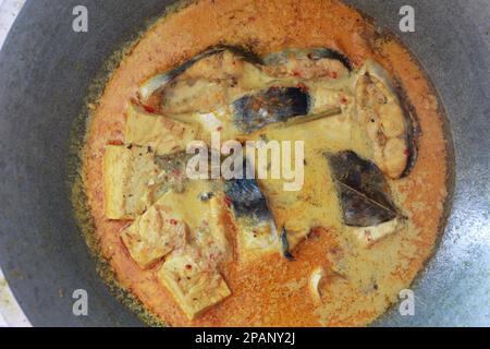 photo of tuna fish and white tofu in yellow spice sauce on a frying pan. Indonesian traditional food photo concept. Stock Photo