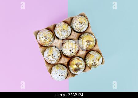 Painted Easter eggs with golden spots in egg carton on blue and violet background Stock Photo