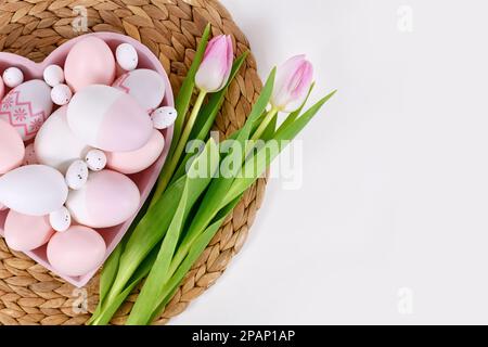 Easter eggs in heart shaped plate and tulip flowers with copy space Stock Photo