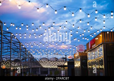 String of light bulb decorations, awning structures for outdoor activities, party, concert, festival, fun fair. Street outside lighted light bulbs gar Stock Photo