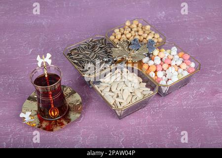 Glass food bowl. Pumpkin seeds, sunflower seeds and chickpeas in glass bowl above, wooden background. Stock Photo