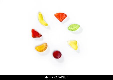 Gummy candies in the form of fruits and berries lies in a circle on a white background. Stock Photo