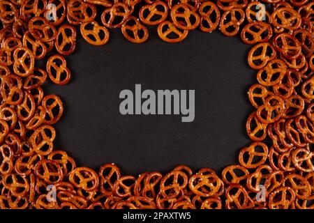 Rectangular frame of mini pretzels on black background. Dark backdrop with Crunchy twists Stock Photo