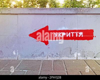 Bomb shelter sign on the building wall. The inscription in Ukrainian SHELTER on the wall. Signpost direction to the bomb shelter in Ukrainian. KYIV, U Stock Photo