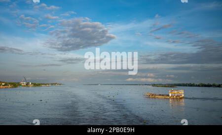 A crowded river ferryboat crosses the Mekong River just after dawn downstream from Phnom Penh in Cambodia. Stock Photo