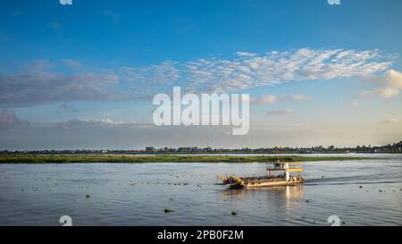 A crowded river ferryboat crosses the Mekong River just after dawn downstream from Phnom Penh in Cambodia. Stock Photo