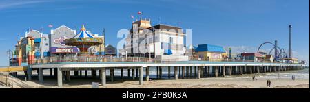 Galveston, Texas, USA - February 2023: Panoramic view of the historic pier on the seafront of Galveston, with people walking on the beach Stock Photo