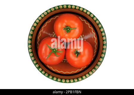 Tomatoes in a clay plate isolate on white background. Red tomatoes in rustic bowl. Stock Photo