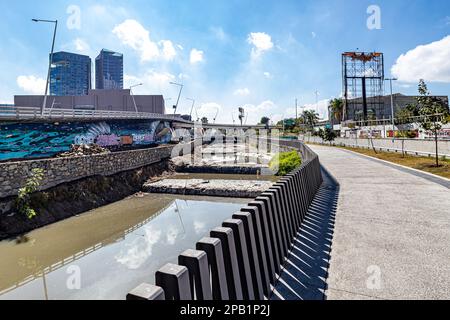 Zapopan, Jalisco Mexico. January 1, 2023. Empty pedestrian walkway along an open sewage canal and a vehicular bridge, modern buildings against a blue Stock Photo