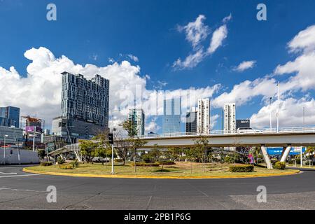 Zapopan, Jalisco Mexico. January 1, 2023. Cityscape with roundabout, elevated vehicular bridge over Acueducto avenue, modern buildings against a blue Stock Photo