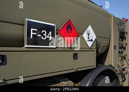 Flammable and dangerous -  Hazardous marine pollutant substance - sign on brown green metal side of army petrol or fuelling vehicle Stock Photo