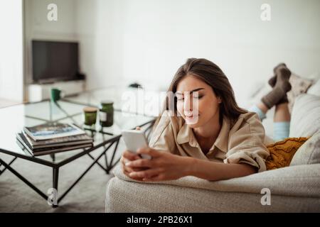 Smiling young asian woman typing on smartphone, chatting in social networks, surfing in internet Stock Photo