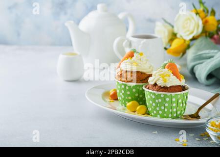 Carrot cake cupcakes for Easter. Carrot cupcakes with cream cheese frosting decorated with tiny marzipan carrots on white background. Happy Easter and Stock Photo