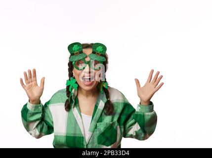 Cheerful woman smiling, looking at camera through stylish carnival eyeglasses in the shape of Leprechaun green hat Stock Photo