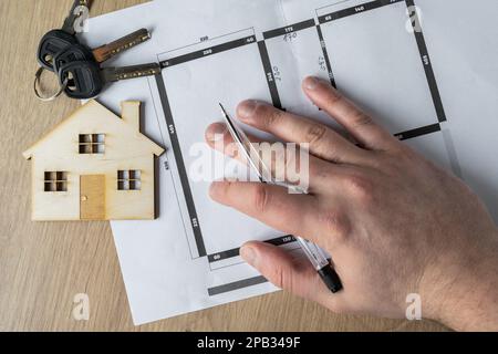 Architect, interior designer or real estate agent hand holding pen. Showing home floor plans. Working on flat or apartment building blueprint project. Stock Photo