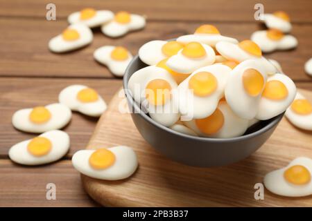 Delicious gummy fried eggs shaped candies on wooden table, closeup. Space for text Stock Photo