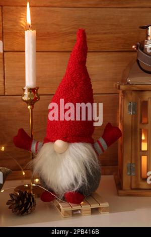 Cute Christmas gnome and festive decorations on mantelpiece in room Stock Photo