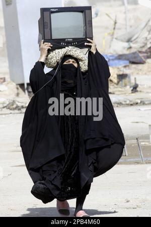 An Iraqi Shiite woman carries a television on her head in a camp outside of Najaf, 160 kilometers (100 miles) south of Baghdad, Iraq on Tuesday, Sept. 11, 2007. The United Nations' refugee agency estimates that about 2,000 Iraqis leave their homes every day due to violence and economic uncertainty resulting from the four-year conflict. (AP Photo/Alaa al-Marjani)
