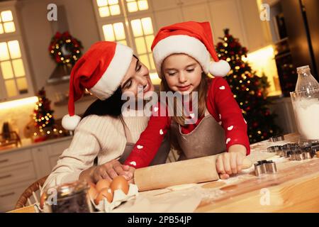 Happy mother and her daughter making delicious Christmas cookies at home Stock Photo