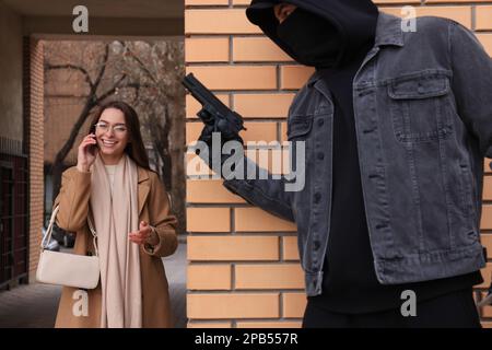 Criminal with gun hiding behind wall and waiting for victim near alley Stock Photo