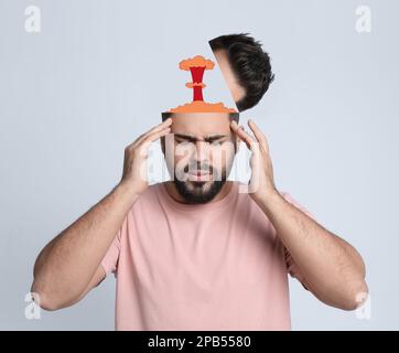 Young man having headache on light background. Illustration of atomic explosion representing severe pain Stock Photo