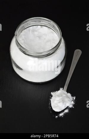 Jar and spoon with baking soda on black background Stock Photo