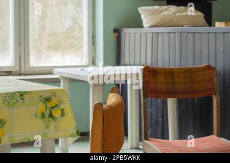 Chairs, a window and a table in an abandoned and dilapidated holiday house in the style of the People's Republic of Poland. Stock Photo