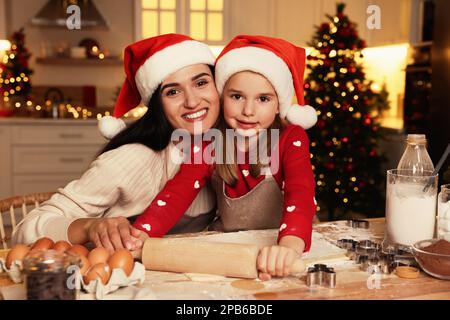 Happy mother and her daughter making delicious Christmas cookies at home Stock Photo