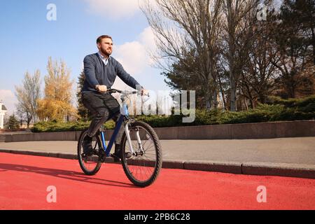 Happy handsome man riding bicycle on lane in city Stock Photo