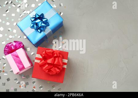 Gift boxes and shiny confetti on grey background, flat lay. Space for text Stock Photo