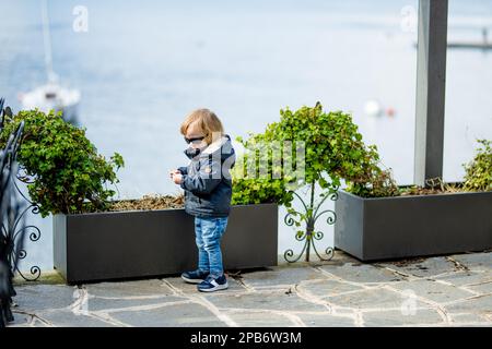 Cute toddler boy having fun exploring on restaurant terrace in Varenna, one of the most picturesque towns on the shore of Lake Como. Varenna, Lombardy Stock Photo