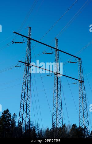 Low angle view of electricity pylons against clear blue sky Stock Photo