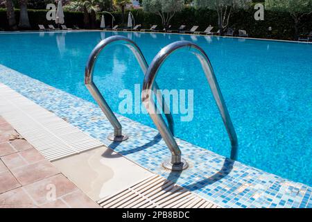 Steps in a Water Pool. Outdoor Swimming Pool with Handrails at Resort on Sunny Day. Stock Photo