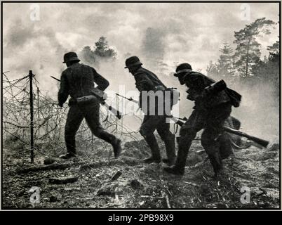 WW2 Nazi Soldiers under fire. German battlefield advance: Nazi Wehrmacht German troops under allied French fire advancing through a barbed wire battlefield front. Ardennes France  photographed by war reporter: Jager. 1940s World War II Second World War Stock Photo