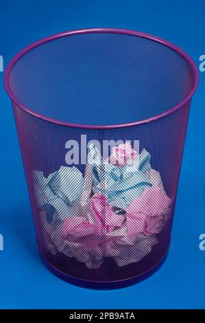 A trash can or rubbish bin containing crumpled paper Stock Photo