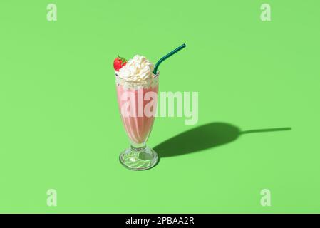 High angle view with a single glass of strawberries milkshake minimalist on a green table. Strawberry flavored milkshake isolated on a green backgroun Stock Photo