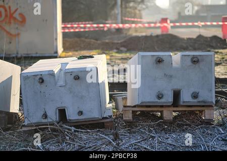 Concrete blocks on pallets prepared for building a railway crossing placed on the ground with railroad infrastructure building in background Stock Photo